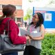 a woman answers questions from another woman with a clipboard outside a hospital